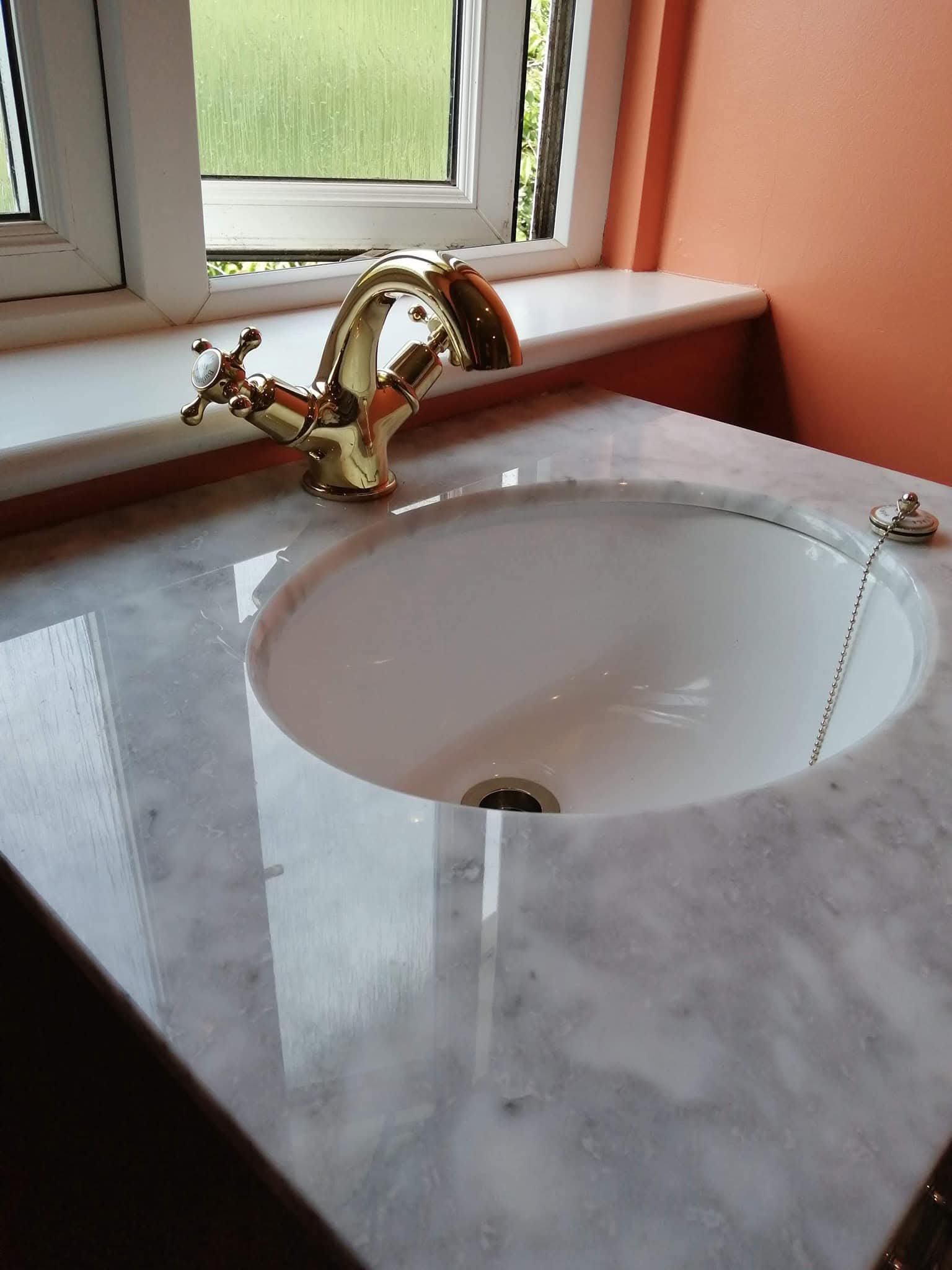 Bathroom basin with brass tap and marble countertop