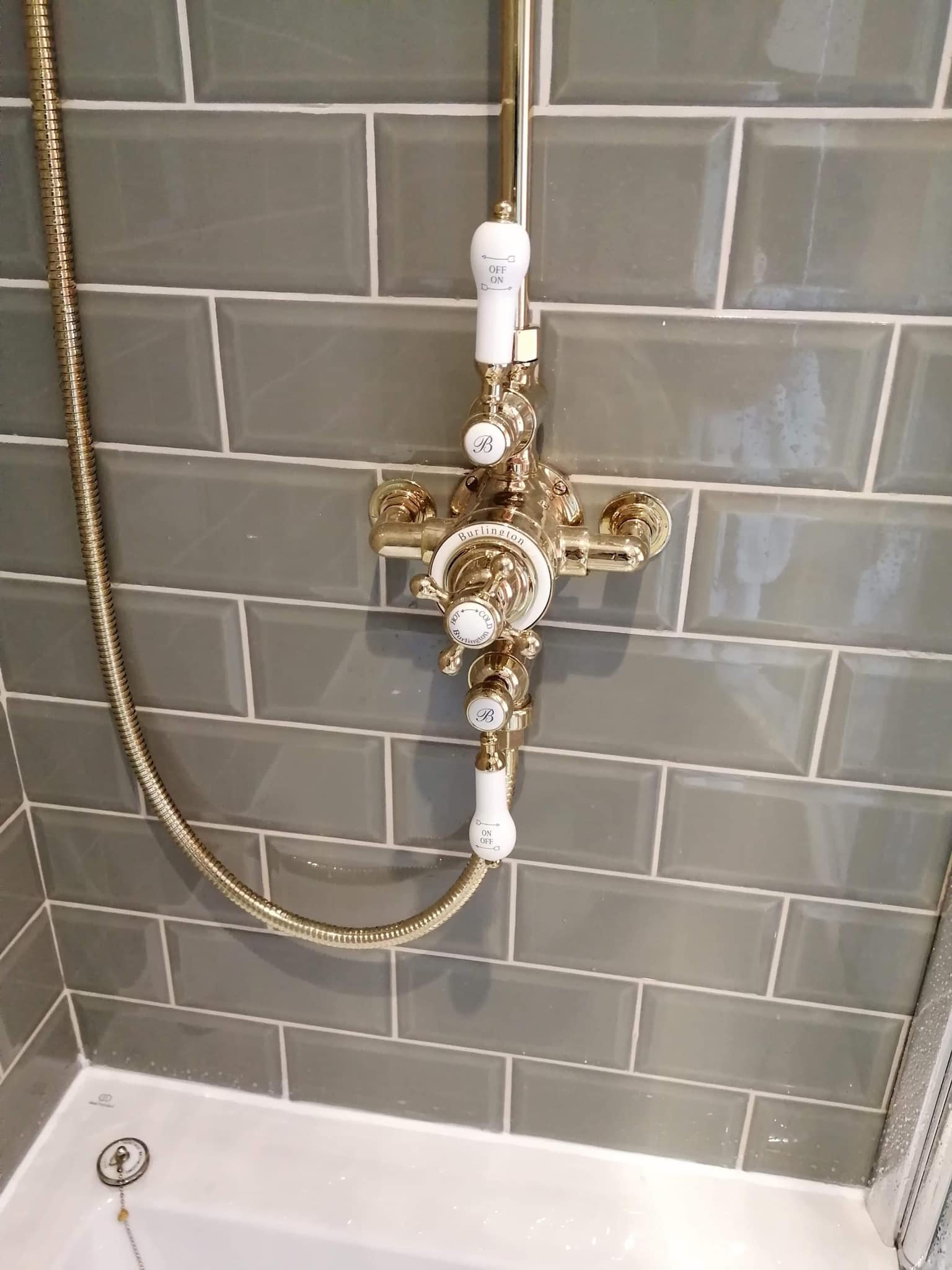 Close-up of brass shower controls on a tiled bathroom wall