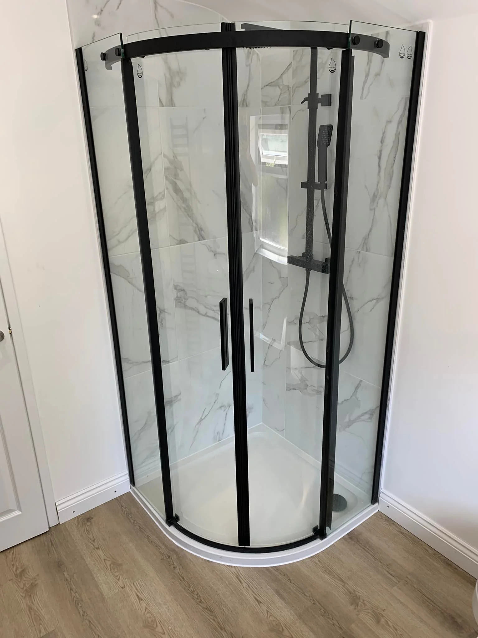 Curved glass corner shower enclosure in a bright bathroom