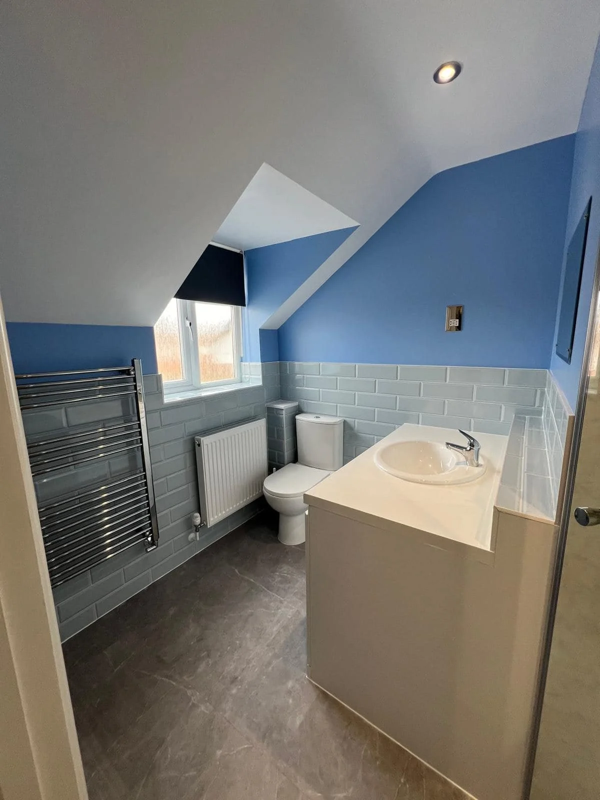 Loft bathroom with blue wall, vanity unit and roof window