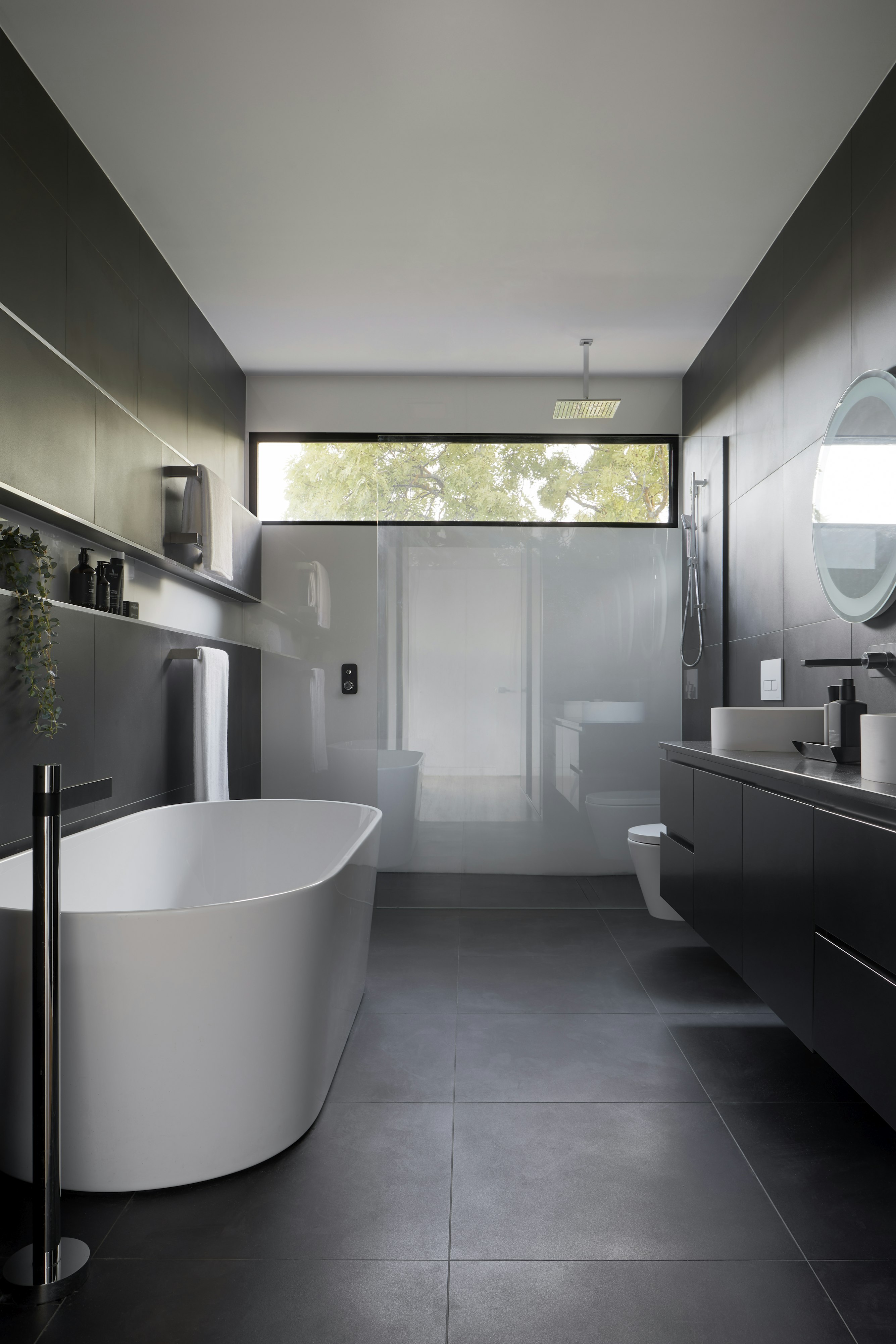 Modern grey bathroom with freestanding bath, walk-in shower and black brassware