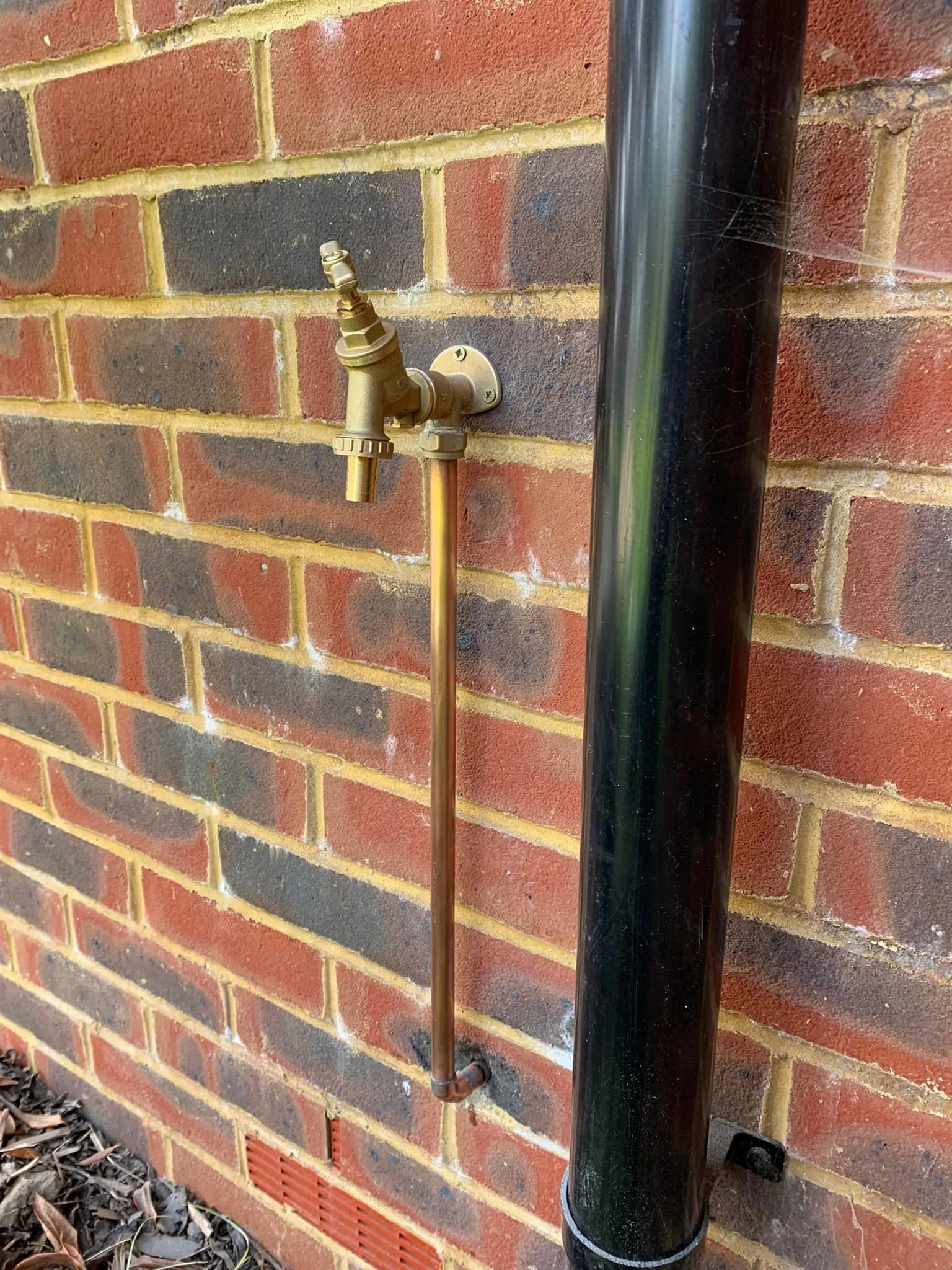 Outdoor brass water tap installed on a brick wall