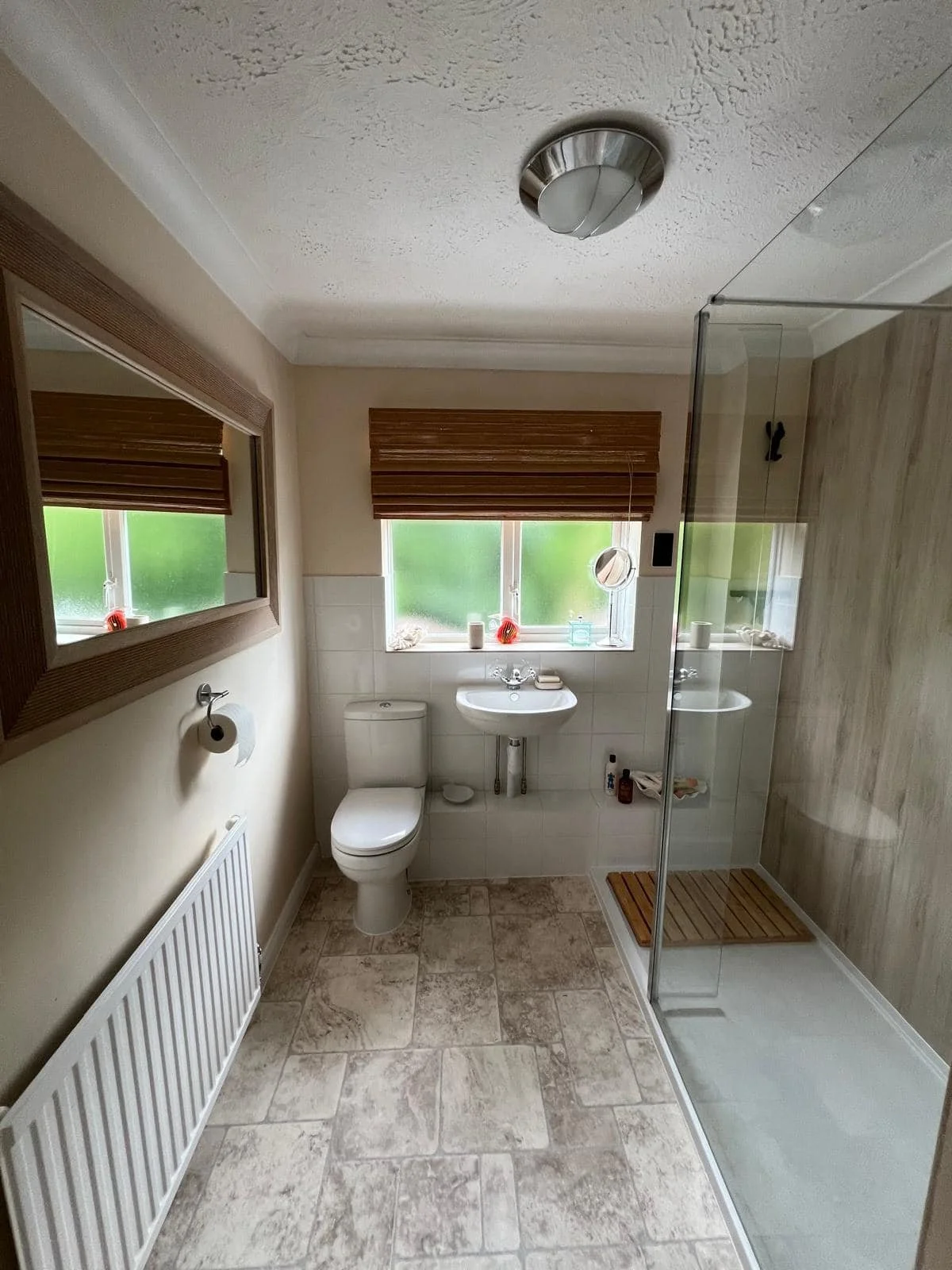 Bathroom walk-in shower with glass screen beside a window